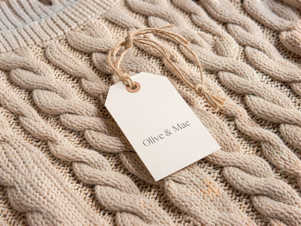 Olive & Mae label on a cream cable-knit sweater
