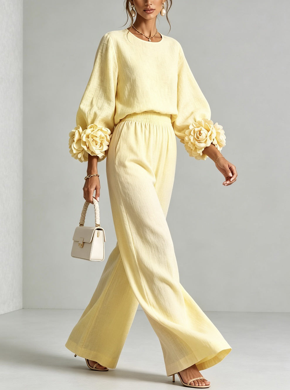 Pale yellow sweater set with wide leg pants, walking with a cream handbag